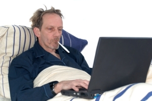 man sick in bed with laptop